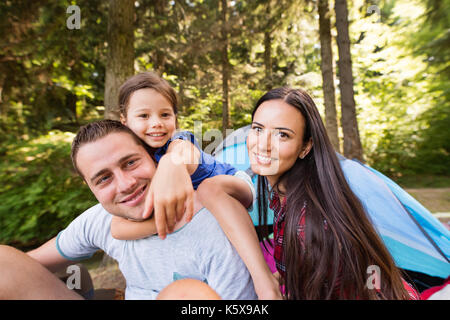 Beautiful young family with daughter camping in forest. Stock Photo