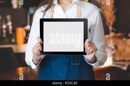 Close up on blank tablet computer that barista show and holding with two hand in front of coffee shop counter bar,Mock up space for display of menu or Stock Photo