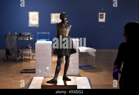 The bronze sculpture 'Little Dancer Aged Fourteen' by Edgar Degas is moved into position, part of a new exhibiton, 'Degas: A Passion for Perfection', at the Fitzwilliam Museum in Cambridge. Stock Photo