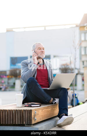 Senior man in town with smart phone, making phone call Stock Photo