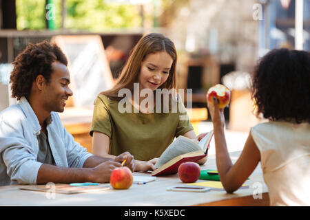 Happy three friends sitting by the table outdoors Stock Photo