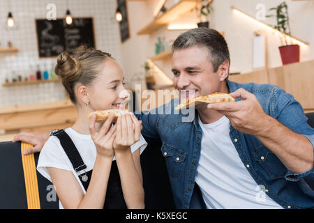 father and daughter eating pizza Stock Photo