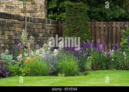 Corner of beautiful, private, traditional, landscaped, country garden,  Yorkshire, England, UK - summer flowering plants bloom on herbaceous border. Stock Photo