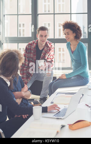 Cheerful students having a funny loud conversation  during break in the classroom of a modern university with international students Stock Photo
