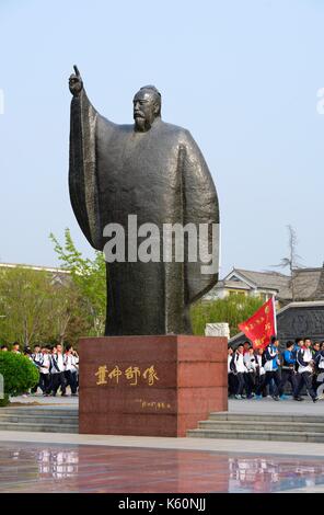 Dongzi Culture Park, City of Dezhou, China. College students parade past statue of Confucian philosopher Dong Zhongshu Stock Photo