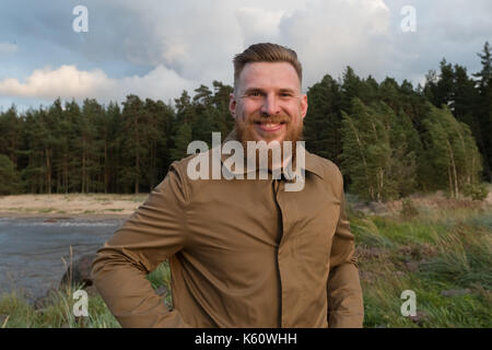 Portrait of a smiling red-haired bearded man in the nature Stock Photo