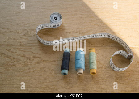Sewing still life - different color cotton thread spools, thimble, needle, measuring tape Stock Photo
