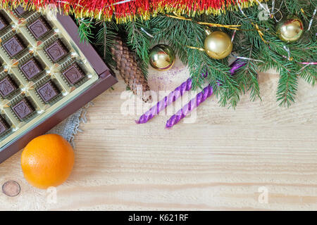 On a wooden table beautifully set decorations and gifts for Christmas, the New year pine branches, cones, shiny balls, candles, confetti. Stock Photo