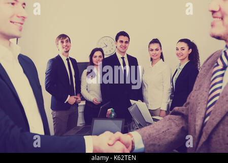 Two managers in suits shaking hands and celebrating successful deal Stock Photo