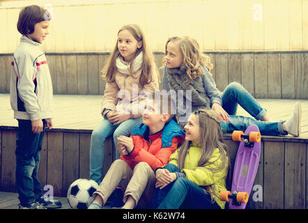 Cute little boys and girls sharing secrets as talking outdoor Stock Photo