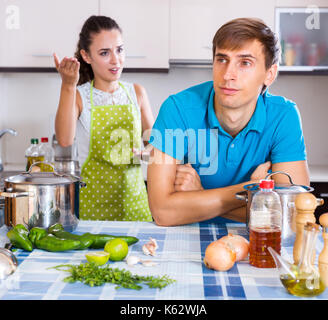 Young family couple with serious faces quarrelling in kitchen at home Stock Photo