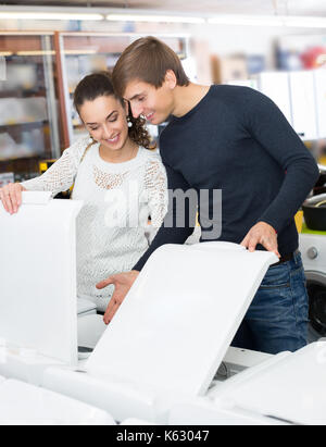 Happy family couple buying new clothes washer in appliance store Stock Photo