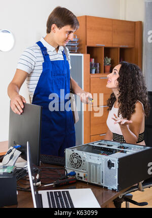 Portrait of positive young woman and PC specialist fixing broken computer Stock Photo