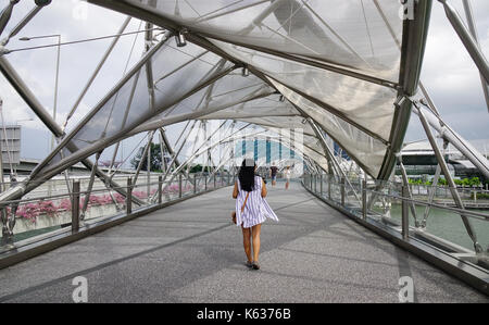 Singapore - Jun 13, 2017. A tourist on Helix Bridge with Marina Bay Sands in background. Tourism in Singapore is major industry and contributor to Sin Stock Photo