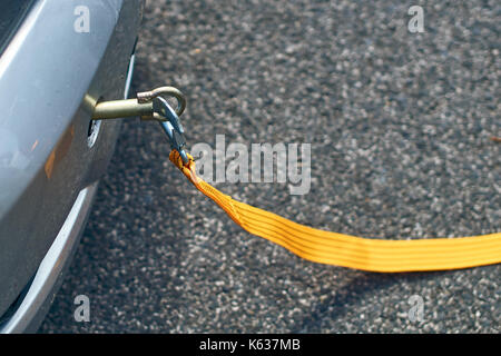 Yellow tow rope attached to a car on the road Stock Photo