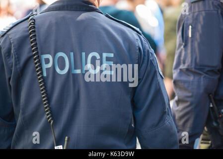 An image of the back of a uniformed policeman on duty wearing blue overalls