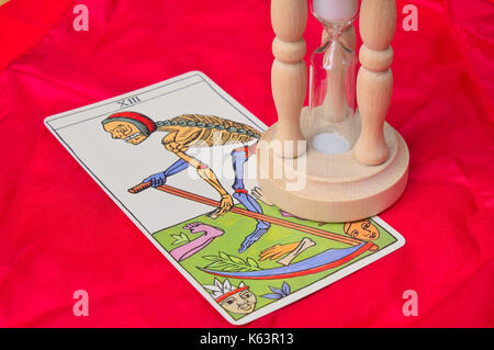 Death tarot card with hourglass on top on a red silk cloth surface Stock Photo
