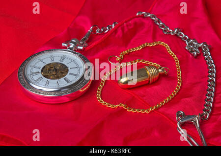 Pocket watch and pendulum on a red silk cloth. Vintage and esoteric theme Stock Photo