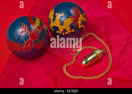 Chinese meditation balls and pendulum on a red silk cloth. Esoteric and mystical themes Stock Photo