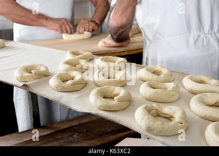 Two male bakers preparing dough for bagels in bakery Stock Photo