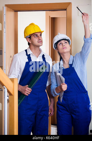 Professional maintenance crew of two european specialists in helmets indoors Stock Photo