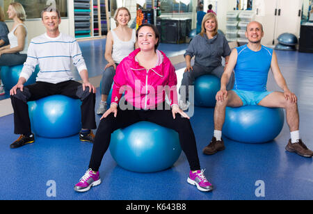 seniors people stretching in a gym on fitness balls Stock Photo