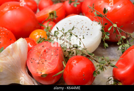 Fresh tomatoes, garlic, onions and thyme in roasting pan ready for roasting to make delicious tomato and basil soup Stock Photo