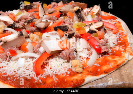 Freshly made pizza with onions, peppers, sausage, cheese and tomato sauce on a peal waiting to be baked Stock Photo