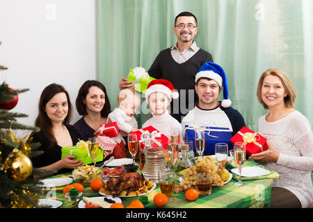 Portrait of big multigenerational family with gifts sitting at festive Xmas table. Focus on girl Stock Photo