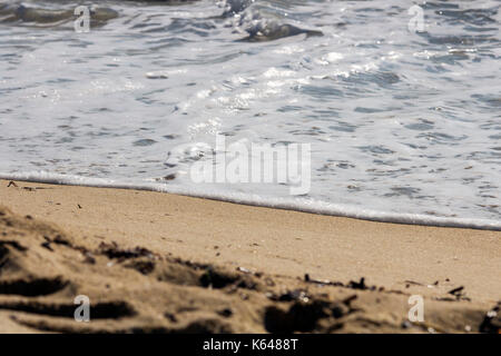 Gentle waves washing up on sandy beach.  Gentle wave motion on a bright sandy beach. Stock Photo