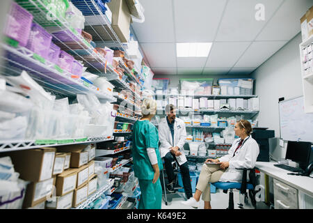 Medical staff discussing in hospital pharmacy. Doctors and nurse talking in hospital pharmacy. Stock Photo