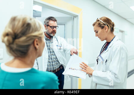 Doctors working in hospital and discussing over medical reports. Medical staff analyzing and working at clinic. Stock Photo