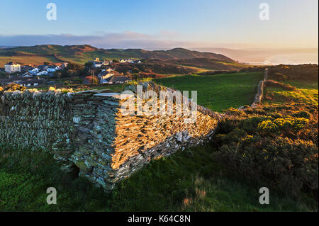 Corner of a dry stone wall in a North Devon field with views of Mortehoe village  and Woolacombe bay in the background Stock Photo