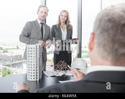 Business presentation of architects for investors, discussing new construction shapes, model of modern multi storey residential building house, bluepr Stock Photo