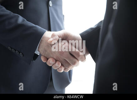 Two businessmen shaking hands standing by windows in office Stock Photo