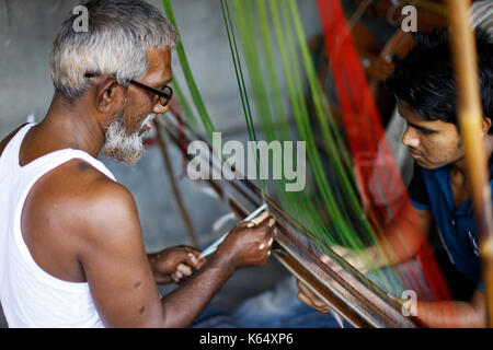 Artisan weaving Jamdani saree on the traditional handloom at Rupganj. Jamdani is a superfine handloom fabric, which has evolved through generations of Stock Photo