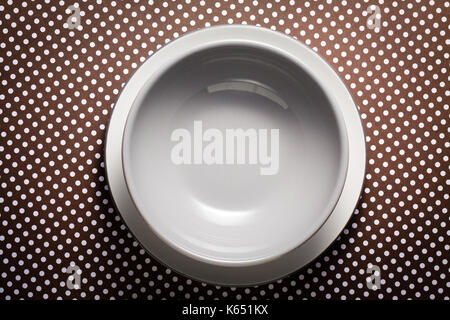 Gray bowl on white plate on dots brown cardboard. Flat lay with copy space. Stock Photo
