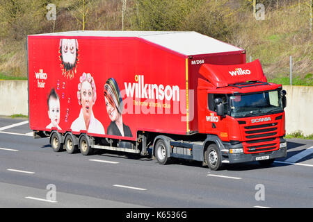 Rebranded red Wilko Scania lorry truck pulling original brand of Wilkinson trailer with advertising graphics on side driving along English UK motorway Stock Photo