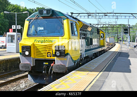 Freightliner mainline freight diesel electric loco 70004 part loaded with shipping containers with some empty wagons passing through Shenfield station Stock Photo