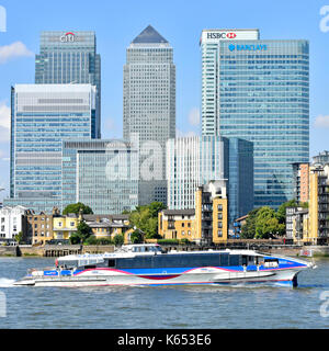 Thames Clipper high speed river bus service passes London Docklands Canary Wharf skyline of banking HQ modern skyscraper buildings beside River Thames