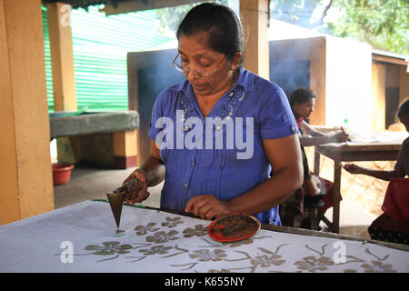 Sri Lanka - January 3, 2017: A woman hand painting fabric in a local Batik fabric factory - store. Stock Photo