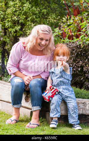 A MODEL RELEASED 2 year old girl with ginger hair outdoors with her mother in the Uk Stock Photo