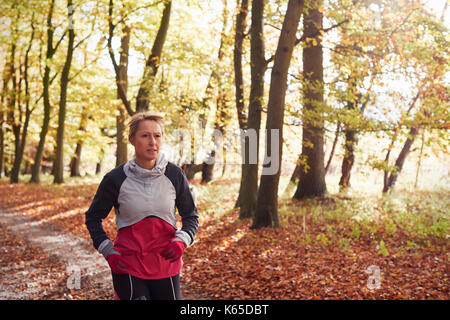 Mature Woman Running Through Autumn Woodland Stock Photo