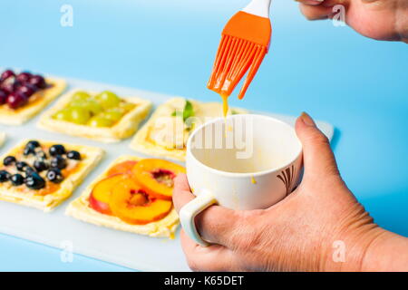 Chef applying egg on the fruit sweet pie before baking Stock Photo