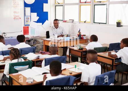 Teacher and kids sitting at desks in elementary classroom Stock Photo