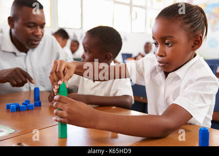 Teacher helping elementary school boy counting with blocks Stock Photo