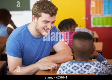 White male Volunteer teacher helping boy in elementary school class Stock Photo