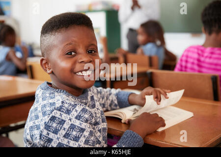 Boy at desk smiling to camera in an elementary school lesson Stock Photo