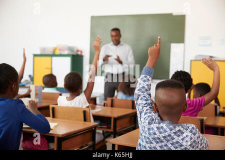 Kids raising hands during a lesson at an elementary school Stock Photo