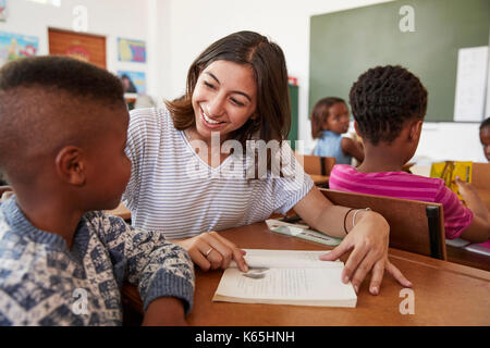 Female teacher helping elementary school boy in class Stock Photo